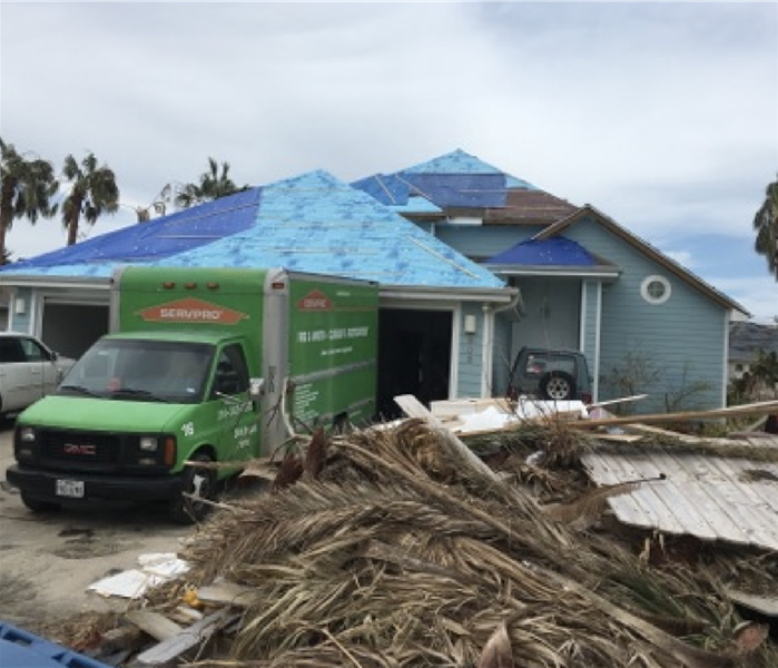 SERVPRO van parked outside home with hurricane damage.