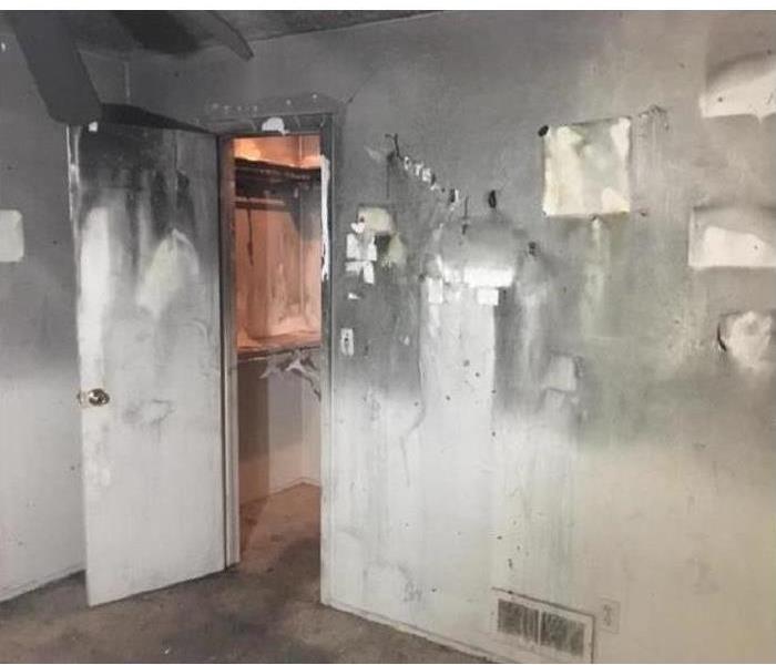 Empty room, door open, door and walls covered with soot caused by fire.