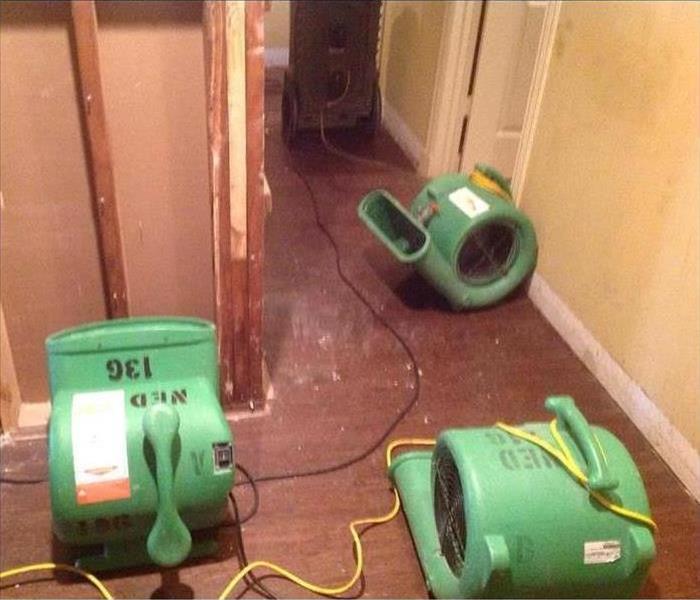 Three air movers placed on a hallway, sheetrock removed.