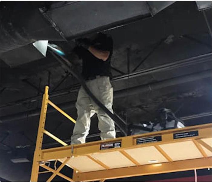 Technician on a scaffold cleaning the ceiling with smoke damage